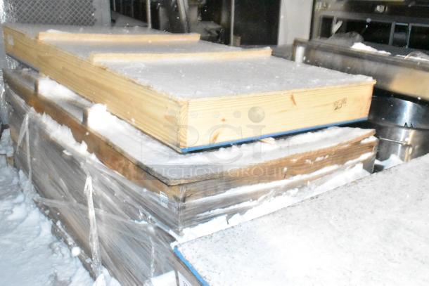 Wooden crates containing brand new items, wrapped in plastic for protection. Snow covers the crates, indicating outdoor storage.