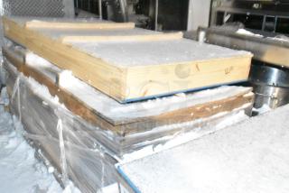 Wooden crates containing brand new items, wrapped in plastic for protection. Snow covers the crates, indicating outdoor storage.