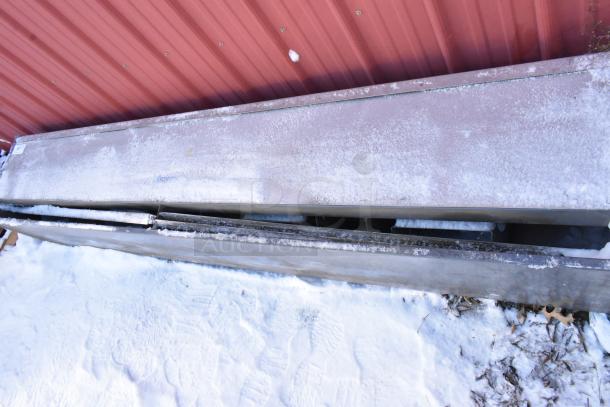 Berner Metal Unit, rectangular, snow-dusted, placed outside against a red wall, showing signs of wear.