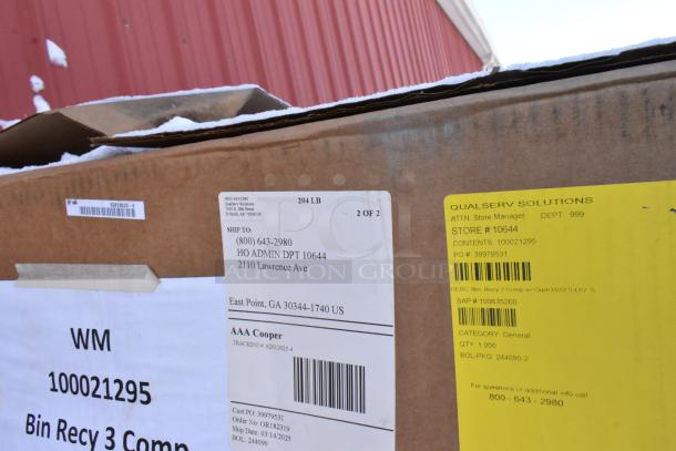 Cardboard box labeled "WM 100021295 Bin Recy 3 Comp" by QUALSERV SOLUTIONS. Shipping details and barcode visible. Snow on top.