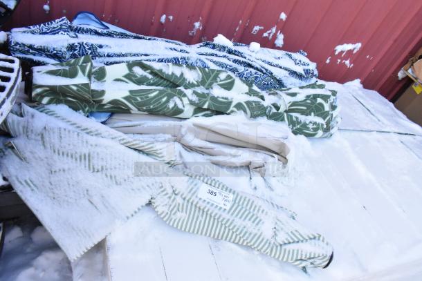 Pallet of assorted patio umbrellas, various colors and patterns, covered in snow. Label reads “385.” Suitable for bulk purchase.