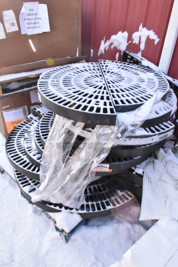 12 black poly semi-circle shelves, stacked and partially wrapped, with snow. Condition appears used. Includes labels.