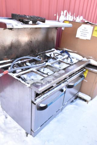 Radiance stainless steel 10 burner commercial range with two ovens, over shelf, and back splash; snow-covered, moderate wear.