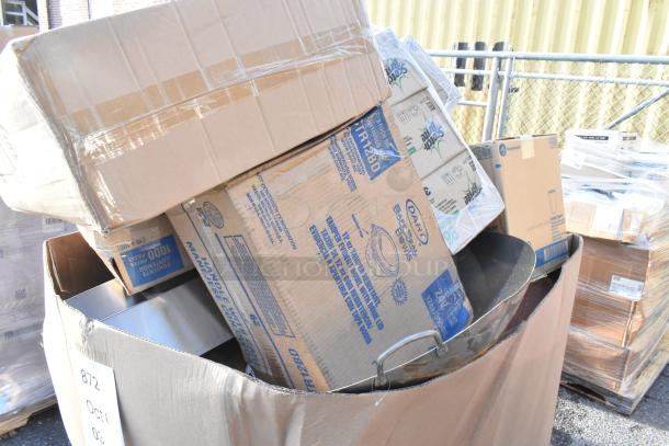 Cardboard boxes containing scratch and dent items like trash cans, napkins, and hot cups are stacked in a large bin.