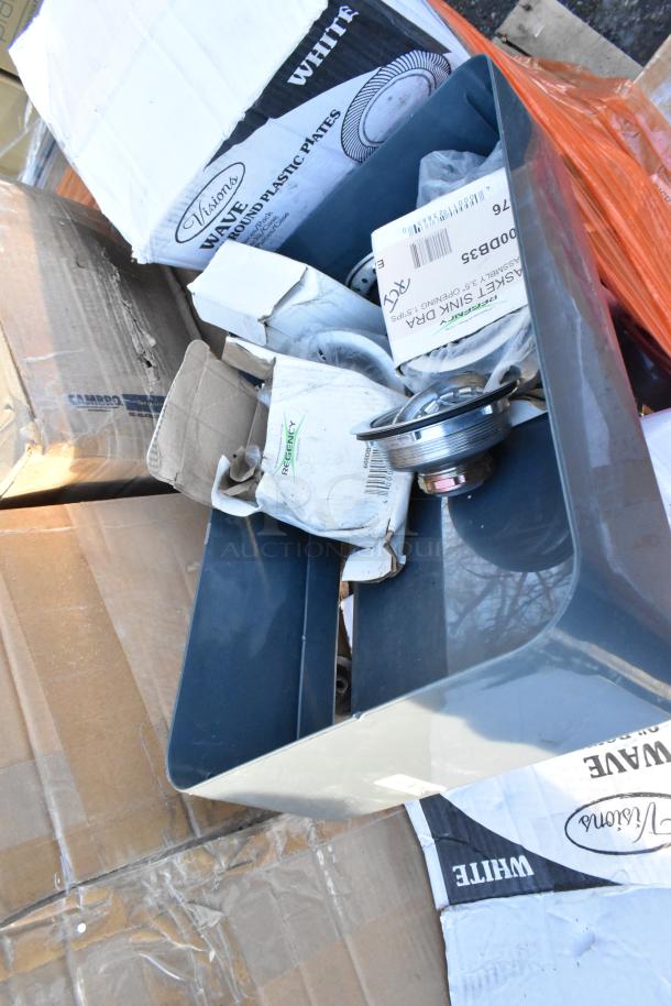Assorted scratch and dent items including Visions plates, Regency sink drains, and a trash can in packaging.