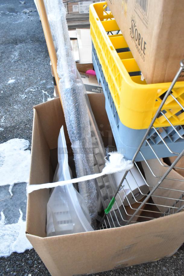 Cardboard box with scratch and dent items, including coffee mugs, food trays, and bowls, next to a Noble Products crate.
