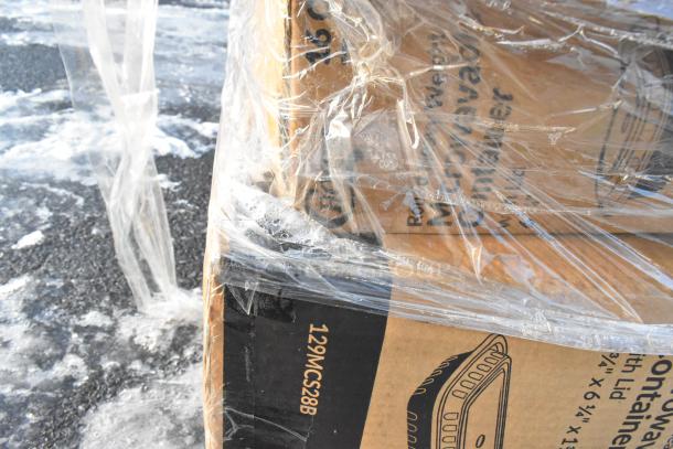 Plastic-wrapped pallet with scratch and dent items, including containers; cardboard box visible with item details printed.