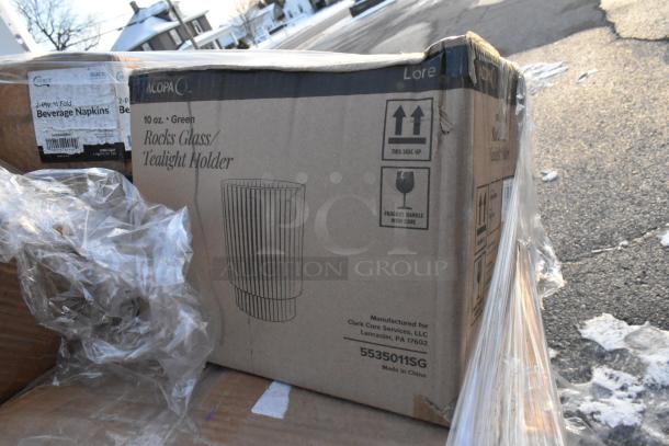 Cardboard boxes containing napkins and 10 oz. rocks glass/tealight holders, labeled "Acopa" and "Clark Core Services."