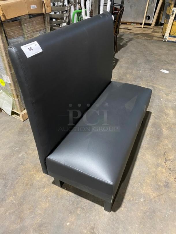 Brand new commercial black upholstered restaurant booth with legs. Features sleek design and durable construction.