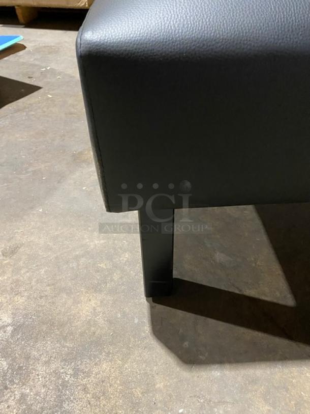 Brand new black upholstered restaurant booth with sturdy legs, commercial grade, seamless finish, pristine condition.
