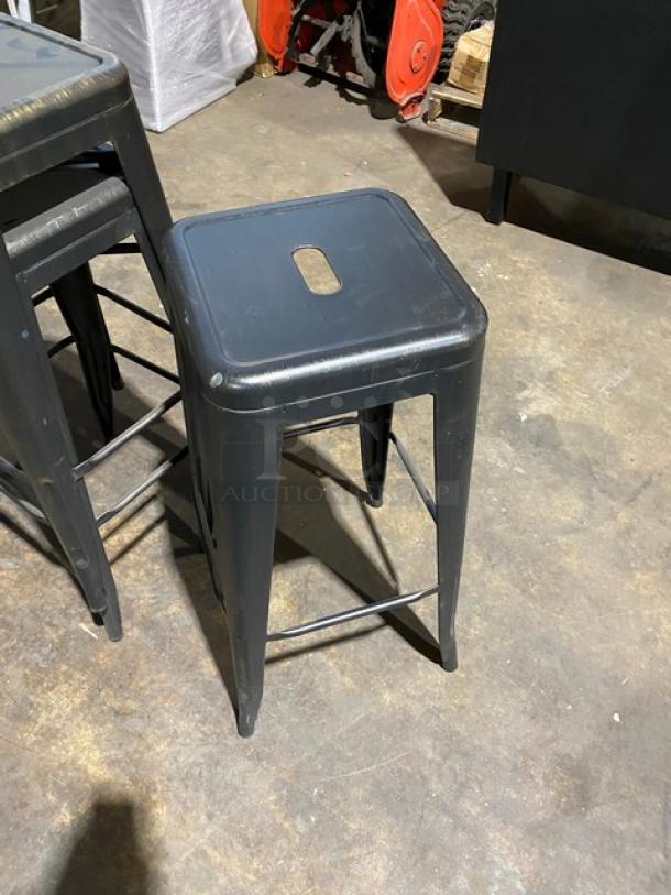 Brand new black metal backless industrial-style stackable bar stool. Sturdy construction, hole in seat for easy handling.