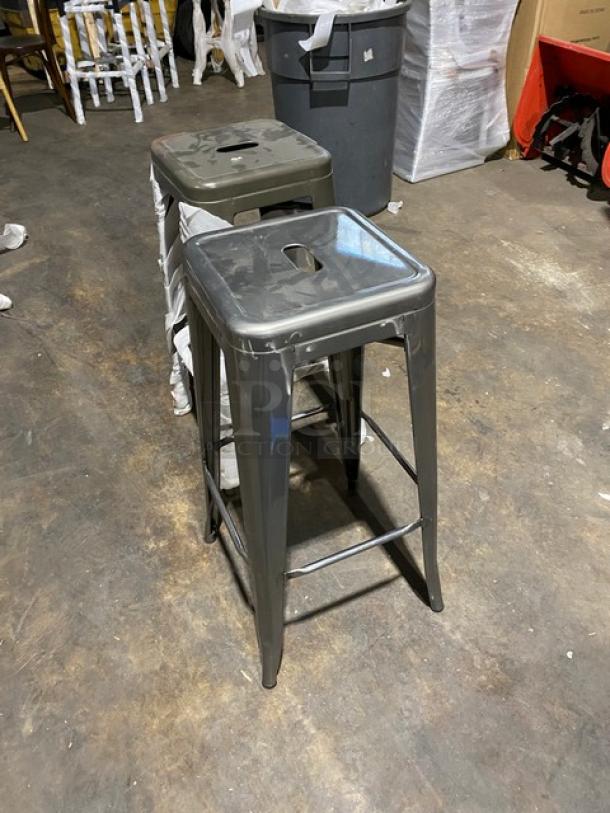 Brand new gunmetal grey industrial-style stackable bar stool, backless, with a smooth metal finish, commercial-grade durability.