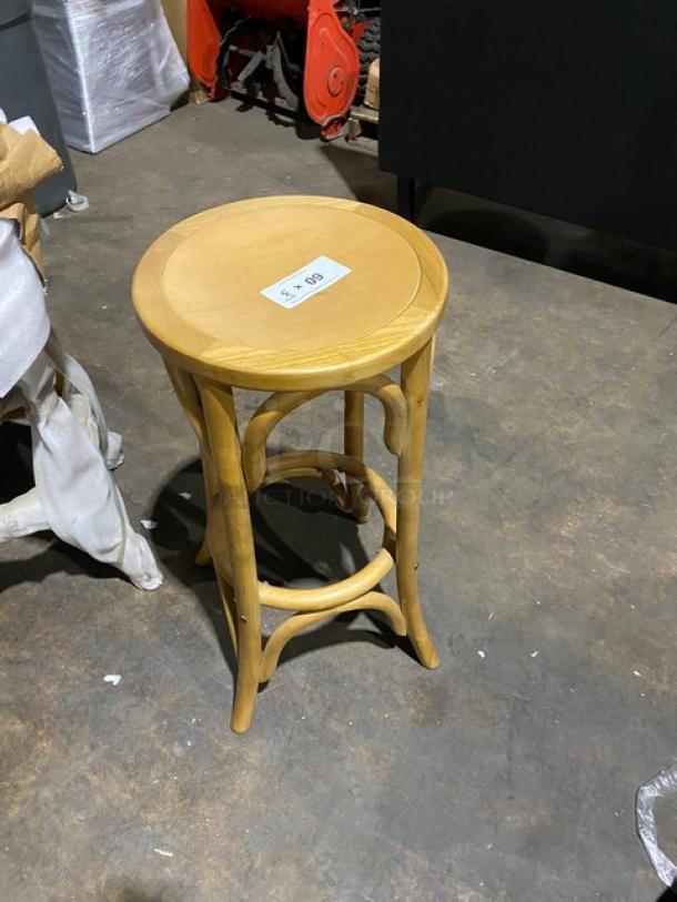 Natural finish backless bentwood bar stool, brand new. Features sturdy round seat and curved legs. Auction tag visible.