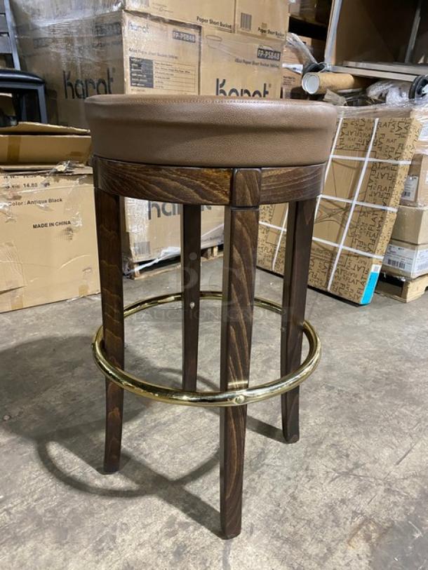 Brand new mid-century modern style brass finish swivel bar stool with tan upholstered seat, wooden legs, and footrest.