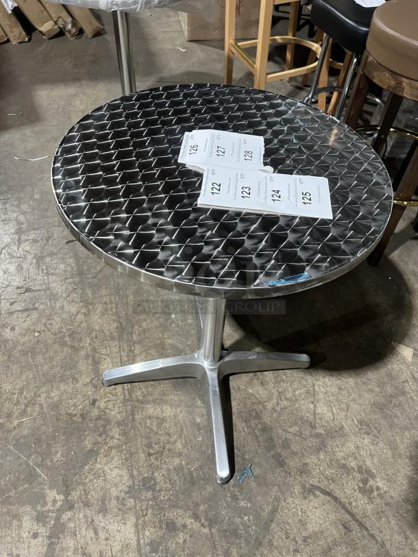 Commercial round bistro table with metallic diamond-patterned top. Features a sturdy four-legged base. Suitable for indoor/outdoor use.