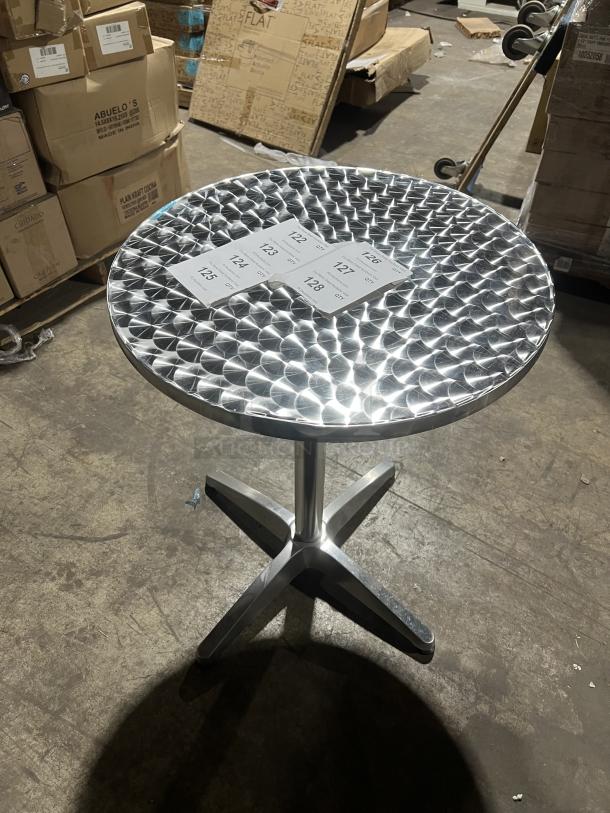 Commercial round bistro table with a polished metal top and cross base, suitable for indoor/outdoor use; excellent condition.