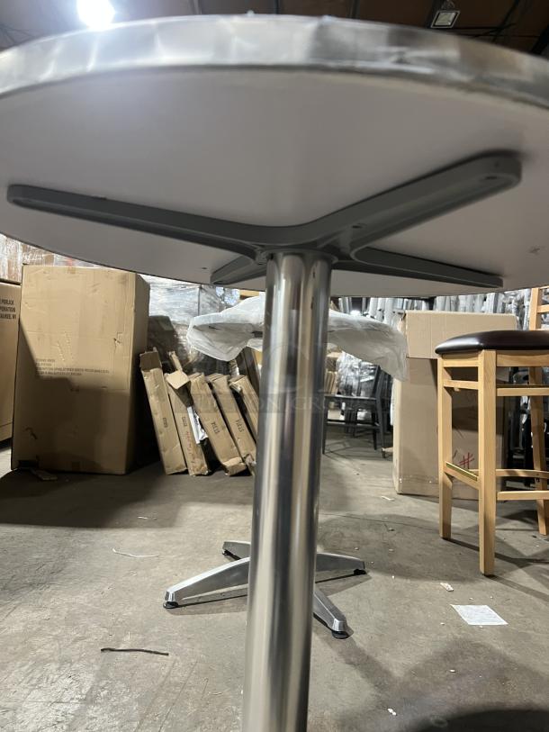 Commercial round bistro table with metal base, suitable for indoor or outdoor use. Appears new, with packaging visible.