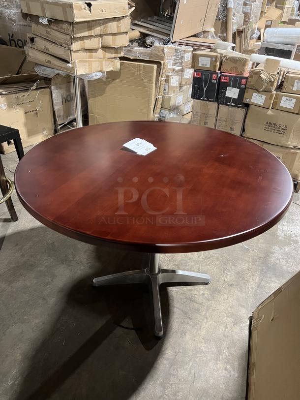 Round mahogany dining table with metal pedestal base, commercial grade, excellent condition, visible inventory tag on top.