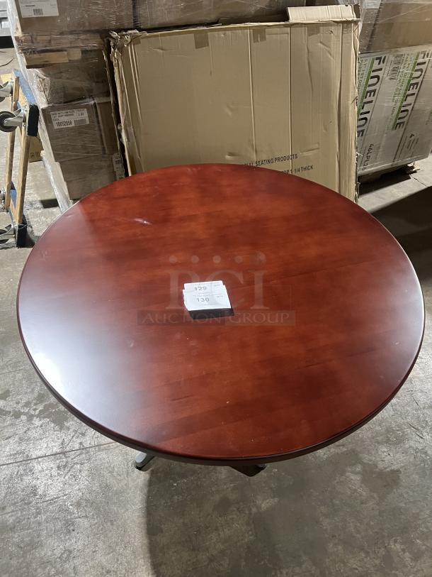 Commercial mahogany round dining table with a sleek metal pedestal base, showcasing a polished finish.