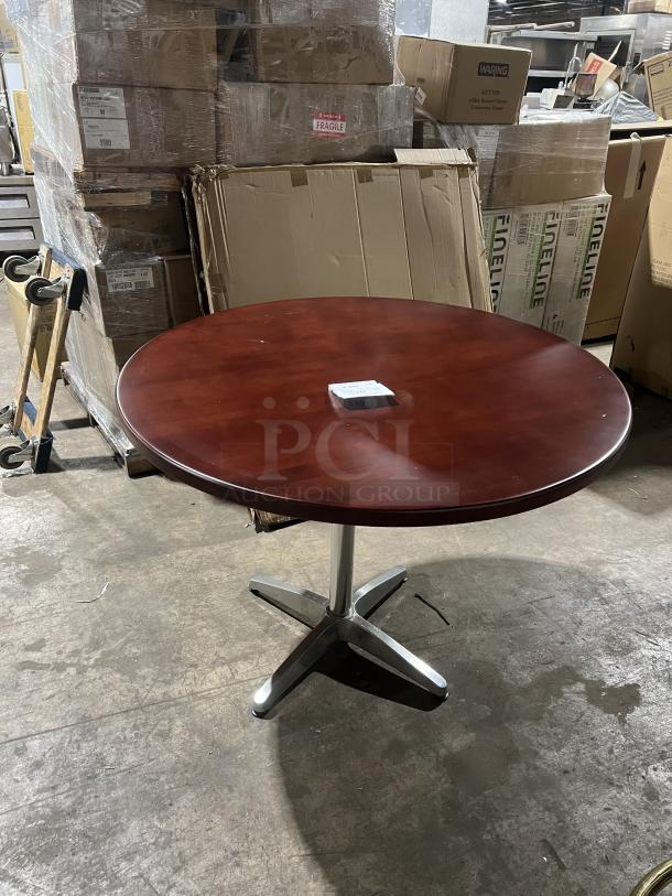 Commercial mahogany round dining table with a metal pedestal base, in good condition. Ideal for dining spaces or businesses.