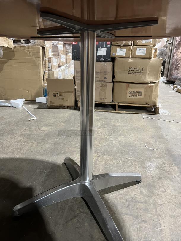 Commercial mahogany round dining table with metal pedestal base, shown in storage. Good condition, sturdy construction.