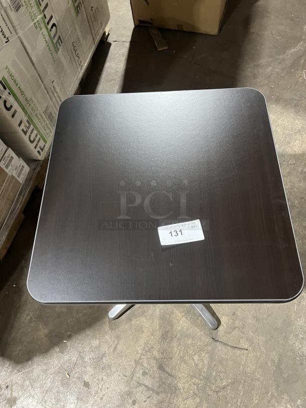 Commercial black square dining table with stainless steel pedestal base. Indoor/outdoor use, modern style. Tag reads "131 QTY."