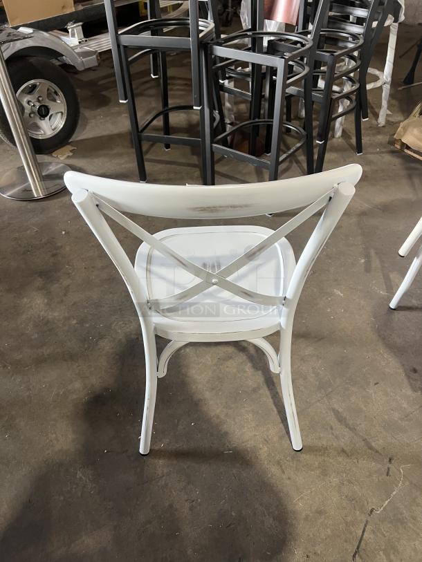 Commercial white cross-back stackable dining chair, metal frame, good condition, ideal for event venues.