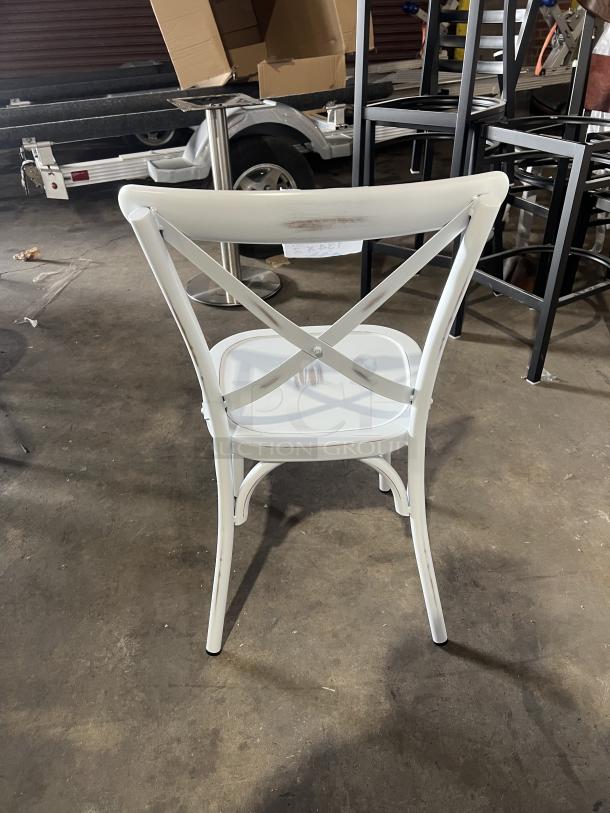 Commercial white cross-back stackable dining chair, metal frame, gently used condition, suitable for restaurants or events.