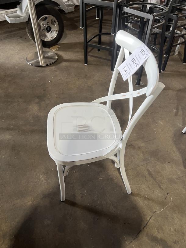 Commercial white cross-back dining chair, stackable, minor wear. Features durable construction, visible labels for identification.