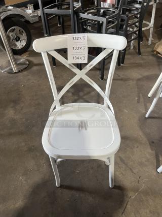 White cross-back stackable dining chair, commercial grade, minor wear on seat, tag numbers 132-134 indicating auction details.