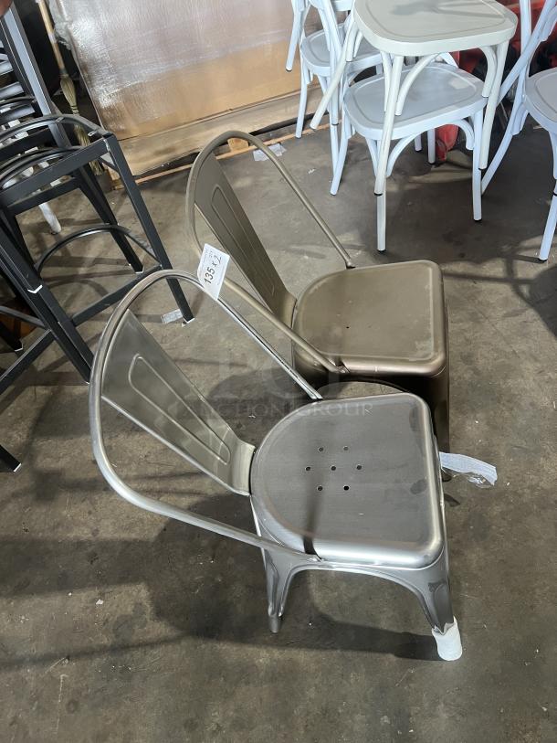Commercial Tolix-style industrial metal stackable dining chair in a silver finish, slightly worn, with visible lot tag 133-42.
