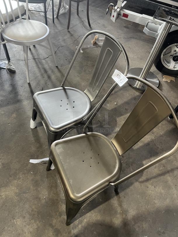 Commercial Tolix-style stackable dining chairs, industrial metal design, minor wear, perforated seats, price tag visible.