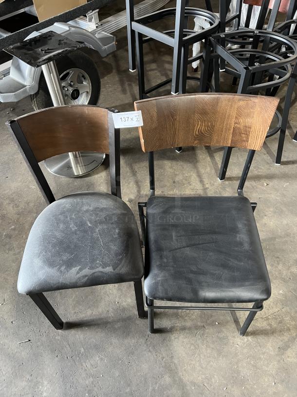 Stackable dining chairs with black padded seats, curved wood backrests, and metal frames. Visible wear on seats. Tag reads "137 x QT 2."