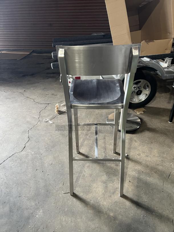 Commercial aluminum bar stool with sculpted seat, curved backrest, and industrial style. Excellent condition.