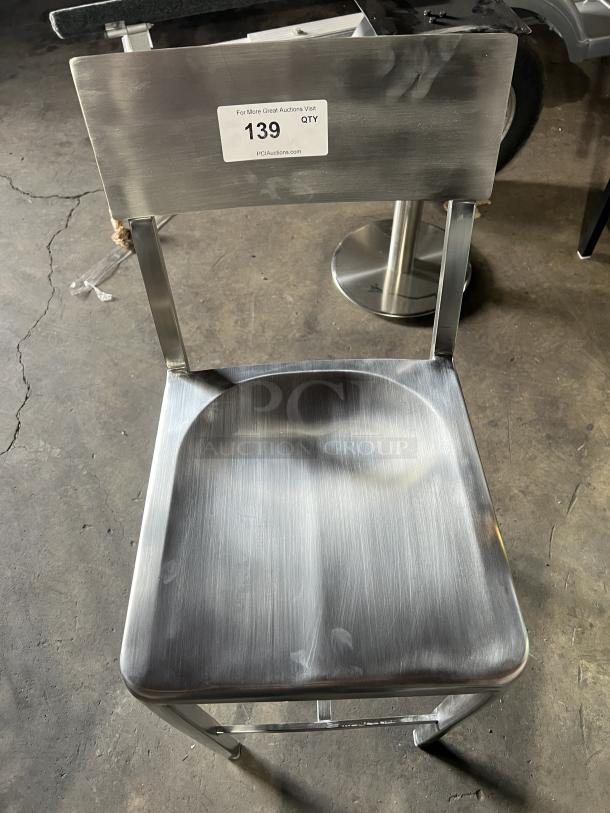 Industrial-style bar stool with sculpted aluminum seat, curved backrest. Lightly used condition. Auction tag reads: PCI Auctions.