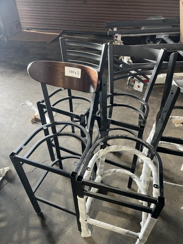 Brand new miscellaneous dining chairs, black metal frames, wrapped parts, wooden backrest, tag indicating quantity, unused.