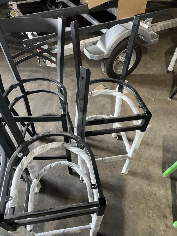 A lot of brand new miscellaneous dining chair frames with black metal construction, partially wrapped, in excellent condition.