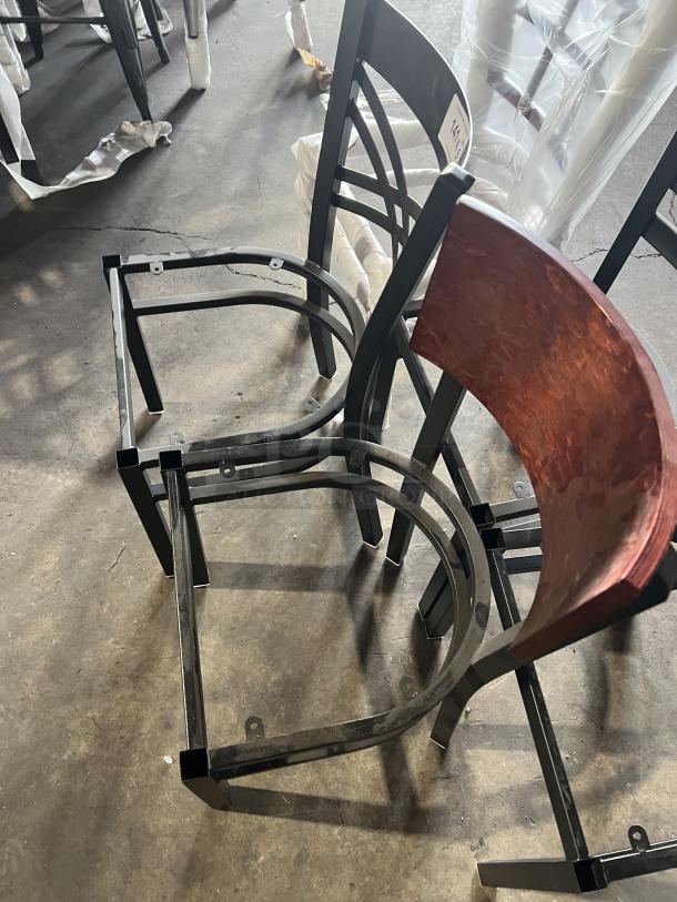 A lot of brand new miscellaneous dining chairs with metal frames and various designs. Some chairs have red wood backrests. Tags visible on frames.