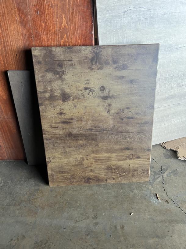 Wooden tabletop with natural grain finish, resting against a surface. No visible markings. Suitable for versatile use.