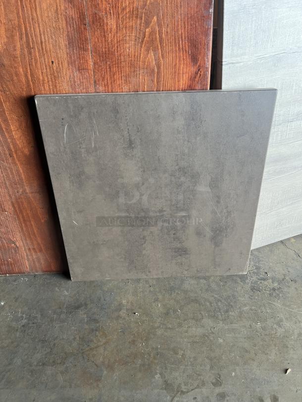 Stainless steel table base with wooden square and rectangular tabletops, various styles and finishes, slight wear visible.