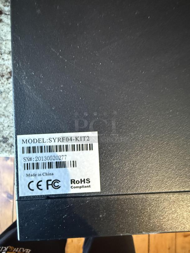 Model label on CCTV Security System SYRF04-KIT2. Serial: 20130520277, CE, FCC, RoHS compliant, made in China.