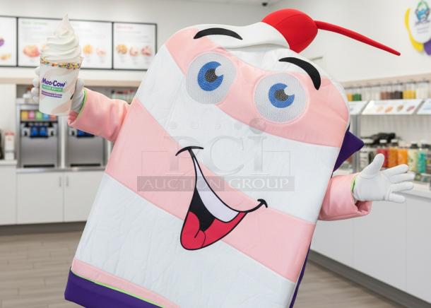 Cheerful cow mascot costume resembling a dessert cup with pink stripes, fun face, cherry, and straw, ideal for promotions.