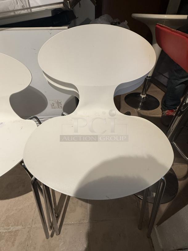 Set of 8 white Arne Jacobsen Series 7 dining chairs with hourglass silhouette and chrome legs. Stackable, modern design.