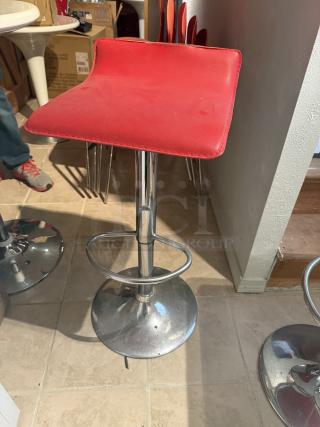 Red bar stool with 29" adjustable height and 360° swivel, chrome base. Minor tear on seat, suitable for cafes or breakrooms.