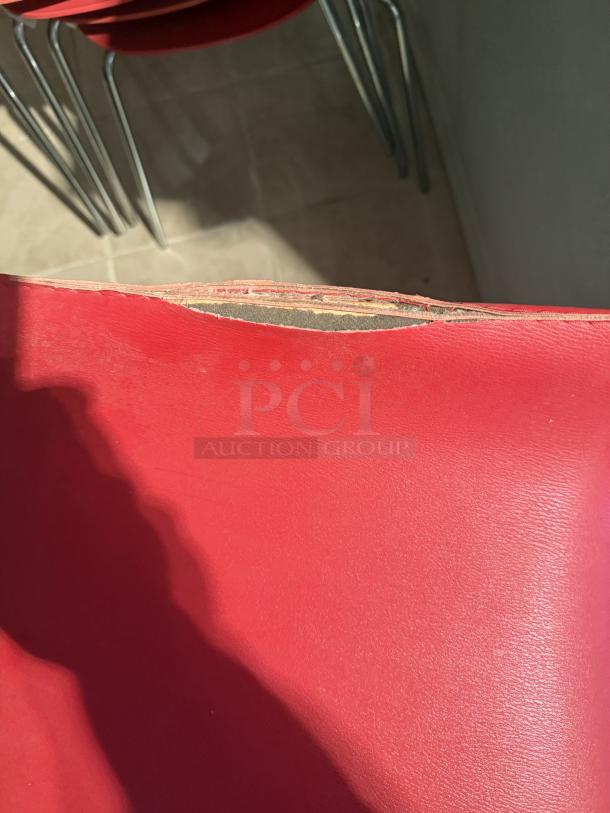 Red bar stool seat with a small tear on the edge. Bright, modern design; 29-inch adjustable height, 360° swivel. Ideal for cafes.