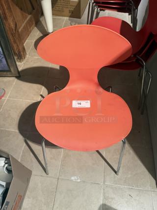Modern mid-century style dining chair in bright red, featuring a distinct 'ant' silhouette with ergonomic design. Label reads "16 QTY".
