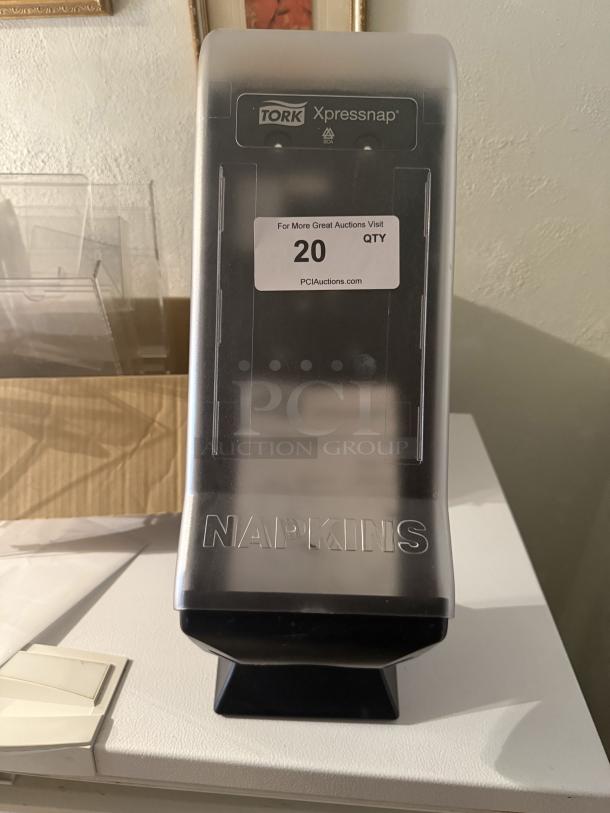 Tork Xpressnap countertop napkin dispenser, high-capacity, professional-grade, reduces waste. Label reads "Tork Xpressnap".