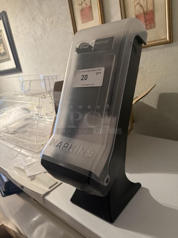 Tork Xpressnap countertop napkin dispenser, clear and black, excellent condition, with label for auction details.