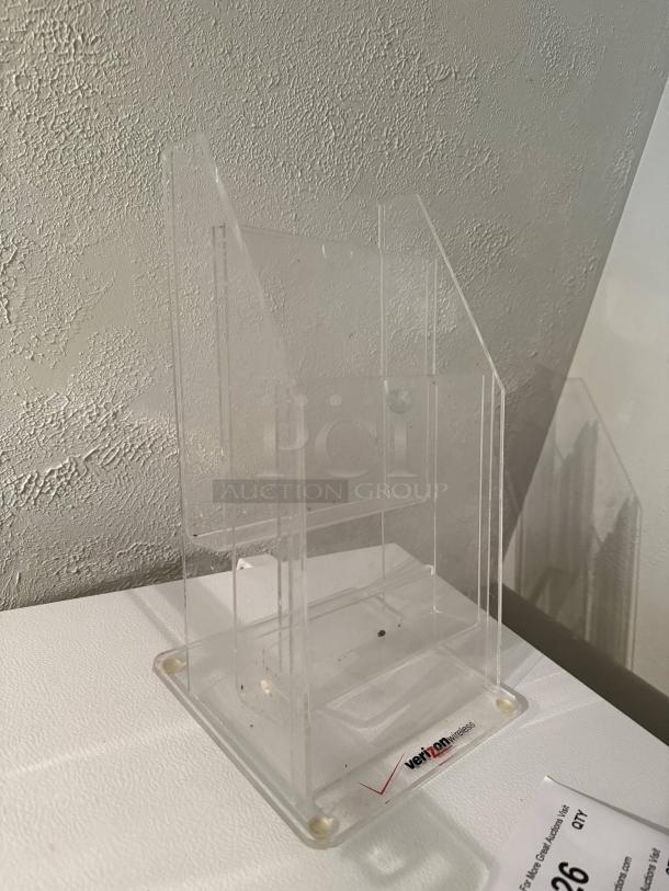Clear 4-tier acrylic pamphlet holder, perfect for displaying tri-fold brochures, holds 75 per pocket, minor wear visible.