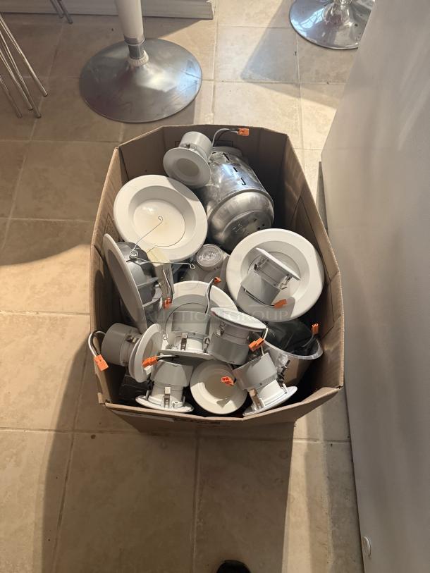 Box of 13 used modern LED recessed light fixtures, including flat discs and smaller trims with orange quick-connects.